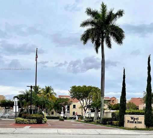 Front view of a residential complex with palm trees and entrance signage.