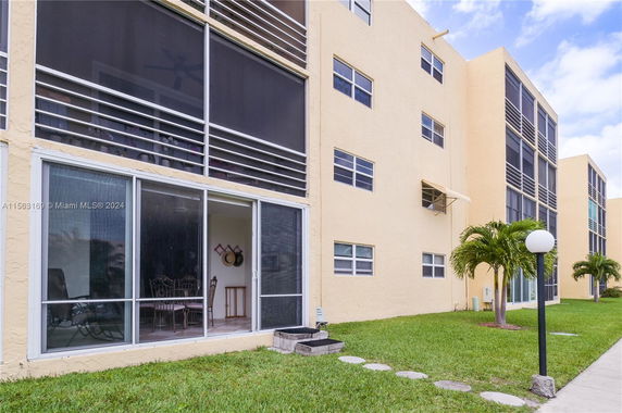 Front view of a multi-story building with large windows and a grass lawn.