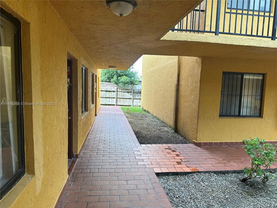 View of a building's exterior walkway with yellow walls and windows.
