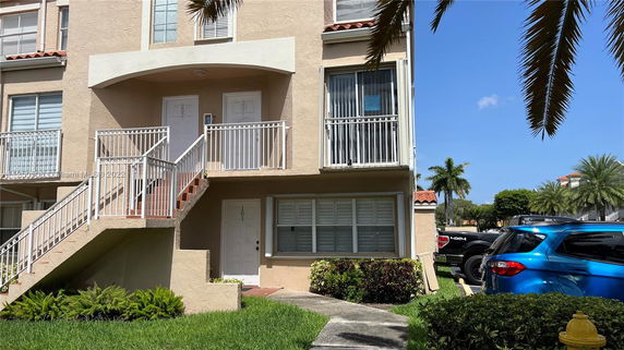 Front view of a multi-story building with external stairs and white railings.
