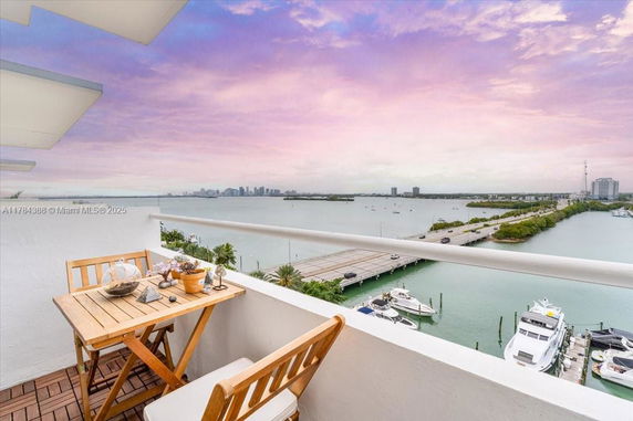 Panoramic view from a balcony overlooking water with boats, a bridge, and distant city skyline.