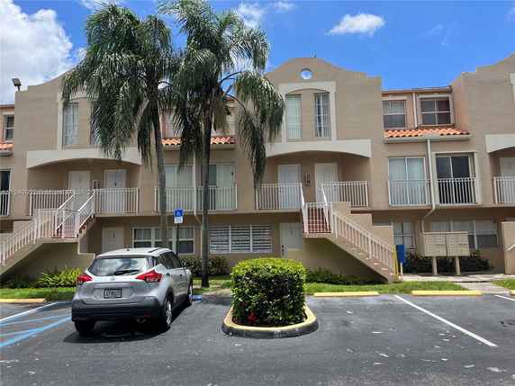 Front view of a multi-story residential building with staircases and parking area.