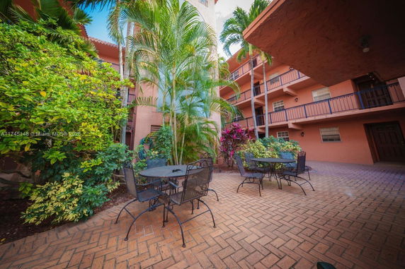 Outdoor courtyard of a multi-story building with patio furniture and lush greenery.