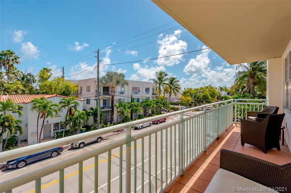 View from a balcony showing streets and surrounding buildings with palm trees.
