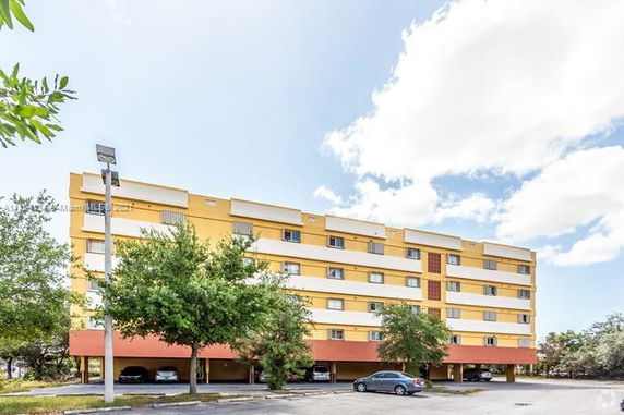 Front view of a multi-story apartment building with parking underneath.