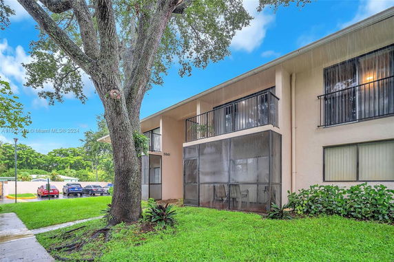Front view of a two-story building with balconies and a screened porch.