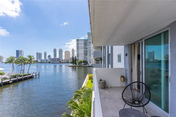 Balcony view overlooking a waterfront with city skyline in the background.