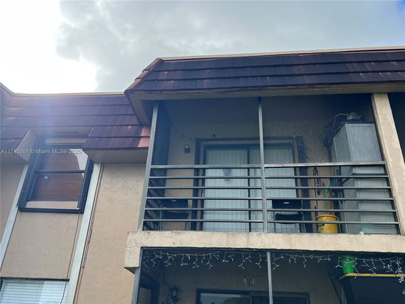 Front view of a multi-story building with a balcony and brown roof.