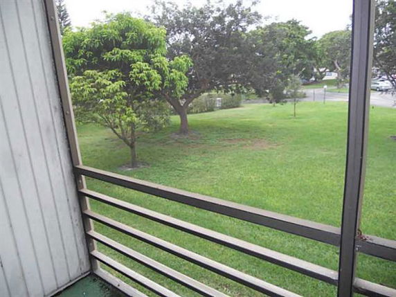 View from a balcony overlooking a grassy area with trees.