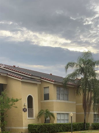 Front view of a two-story building with a tiled roof and arched window.