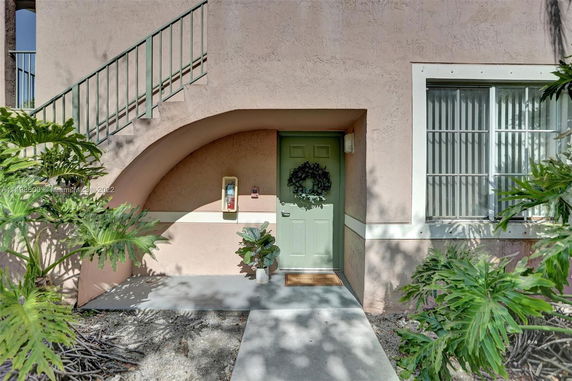 Front view of a building entrance with a green door and staircase.