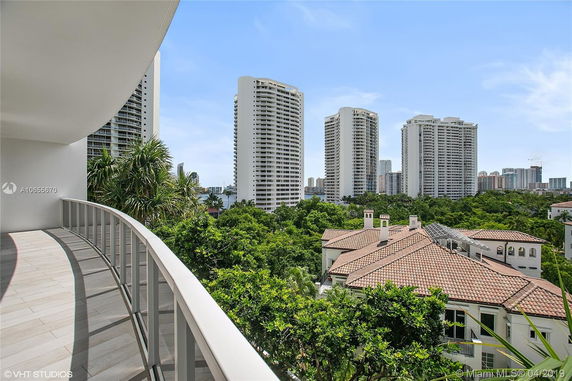 View from a balcony showcasing several high-rise residential buildings and rooftops with greenery in the foreground.