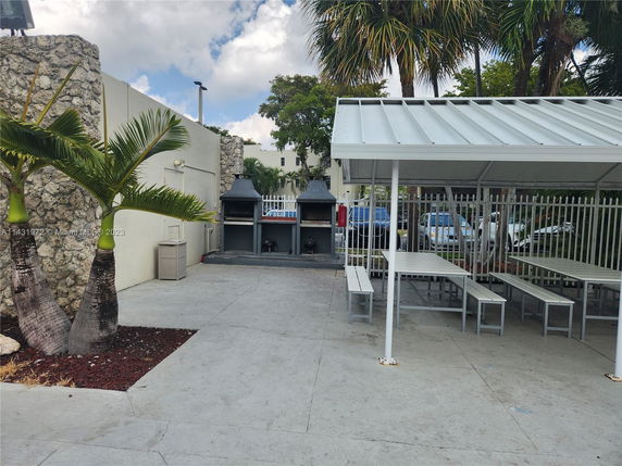 Outdoor area with a covered seating structure and BBQ grills.