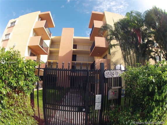 Front view of a multi-story residential building with balconies and a gated entrance.