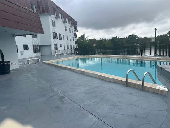 View of an outdoor swimming pool next to a multi-story building.