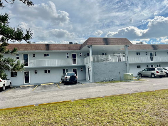 Front view of a two-story building with balconies and parking area.