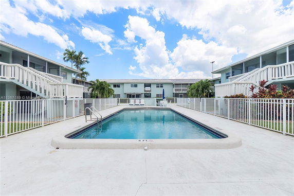 Outdoor swimming pool surrounded by buildings with balconies and staircases.