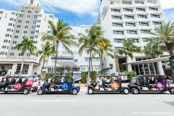 Front view of a multi-story hotel building with palm trees and golf carts in front.