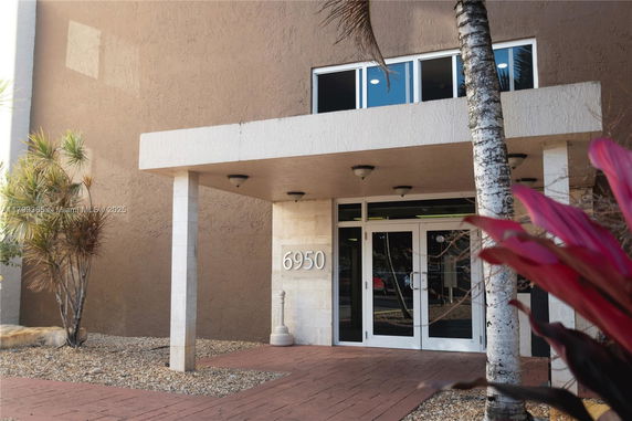 Front entrance of a building with a canopy and glass doors.