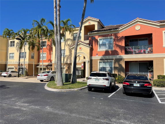 Front view of a multi-story residential building with parking area.