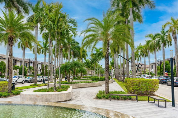 A paved walkway with palm trees and benches in an urban area.