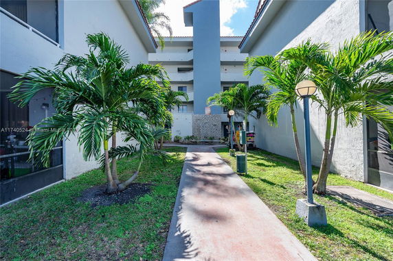 Front view of a multi-story building with a central pathway and surrounding greenery.