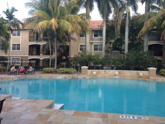 Outdoor swimming pool in front of a multi-story residential building.
