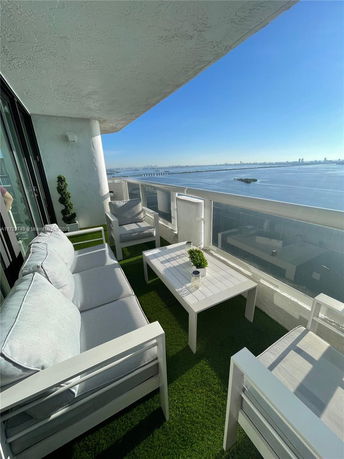 Balcony view overlooking a body of water with city skyline in the distance.