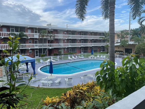 Outdoor view of a swimming pool area with lounge chairs and surrounding apartment building.
