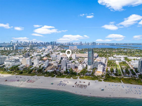 Panoramic view of a beachfront cityscape with tall buildings and a sandy shoreline.