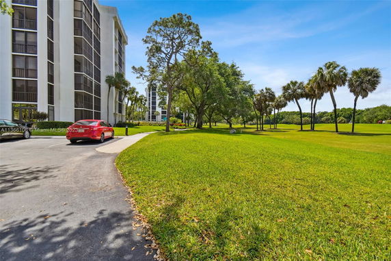 View of an apartment complex with surrounding green lawns and trees.