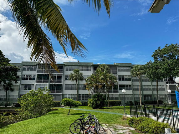 Front view of a multi-story residential building with large windows and surrounding landscaping.