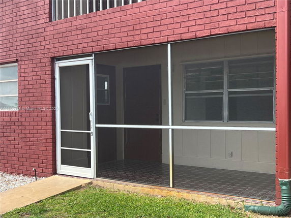 Front view of a brick house with screened porch and windows.