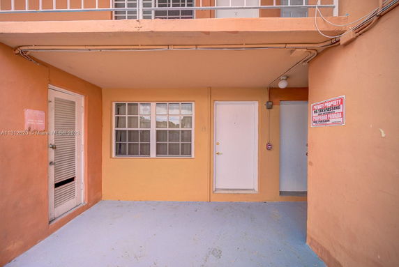 Front view of a multi-story building entrance with an orange facade and multiple doors.