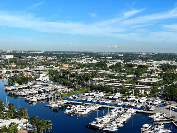 Panoramic view of a marina with numerous boats docked and surrounding urban landscape.