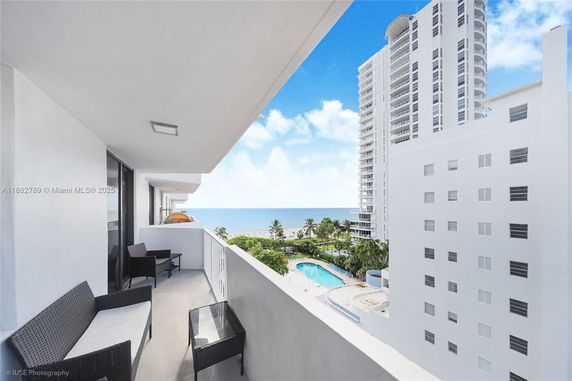 Balcony view overlooking a beach and nearby high-rise buildings.