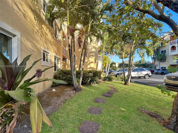 Side view of a multi-story building with a sidewalk and parking area.