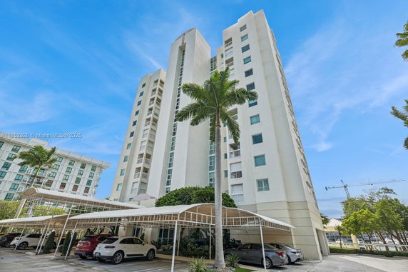 Front view of a tall residential building with a covered parking area.