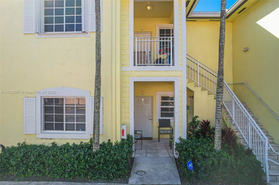 Front view of a two-story yellow building with stairs leading to the upper level entrance.