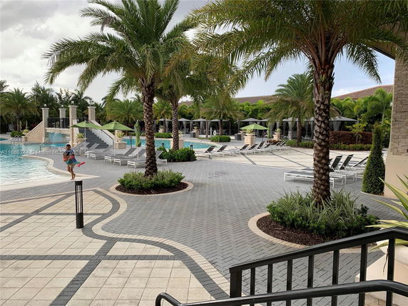 Outdoor swimming pool area with lounge chairs and palm trees.