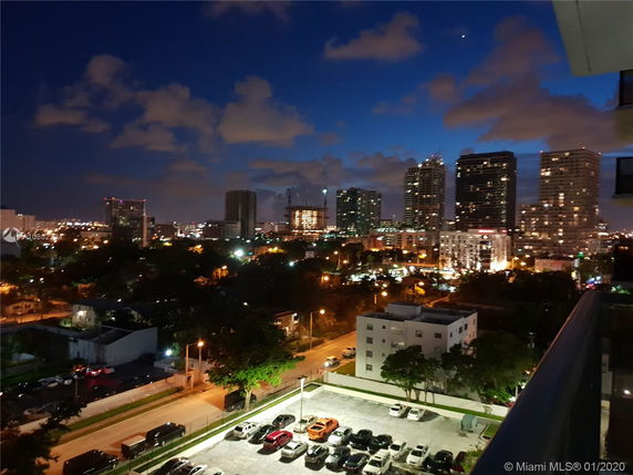 View of city skyline with tall buildings at night from a higher vantage point.