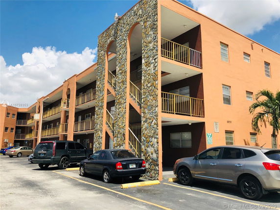 Front view of a multi-story apartment building with parking area.