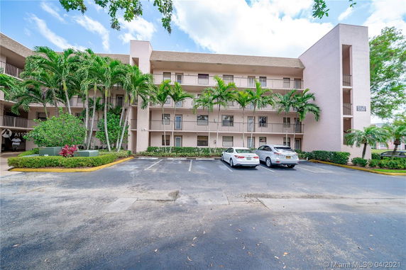 Front view of a multi-story residential building with parking area.