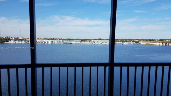 Panoramic view of a large body of water with buildings in the distance seen from a balcony.
