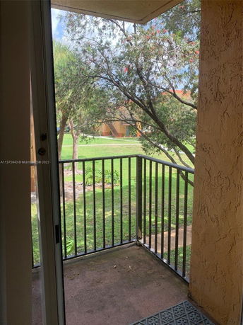 View from a balcony overlooking a grassy area with trees.