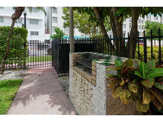 Outdoor area with a brick barbecue grill and a surrounding fence.