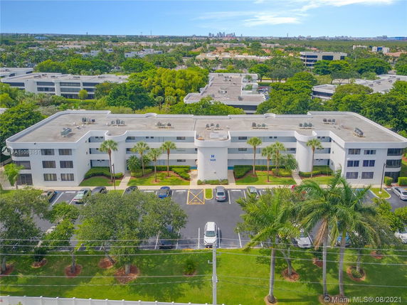 Front view of a multi-story white building with a flat roof and landscaping in front.