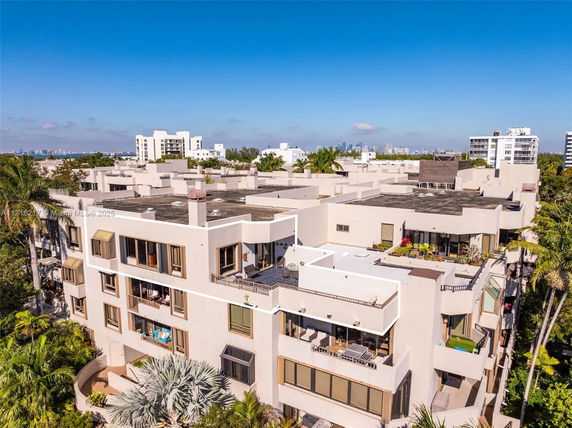 Aerial view of multiple building rooftops with city skyline in the background.