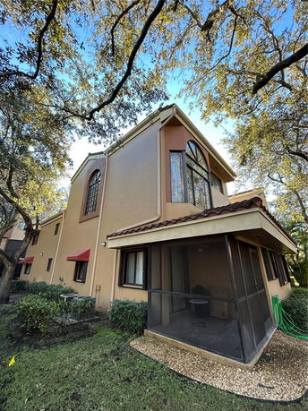 Side view of a two-story house with large windows and a screened porch.