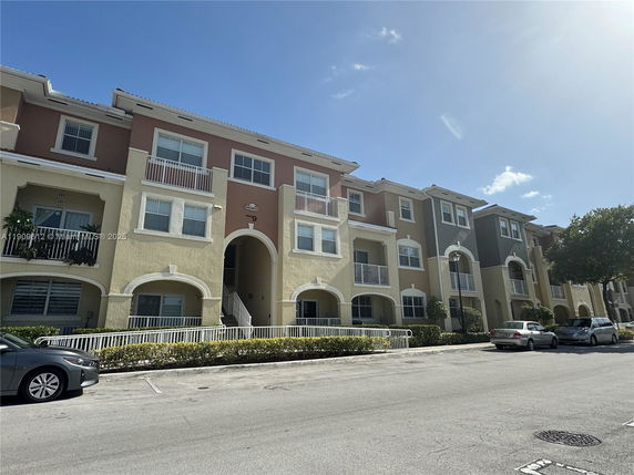 Front view of a multi-story apartment building with balconies and arched entrances.